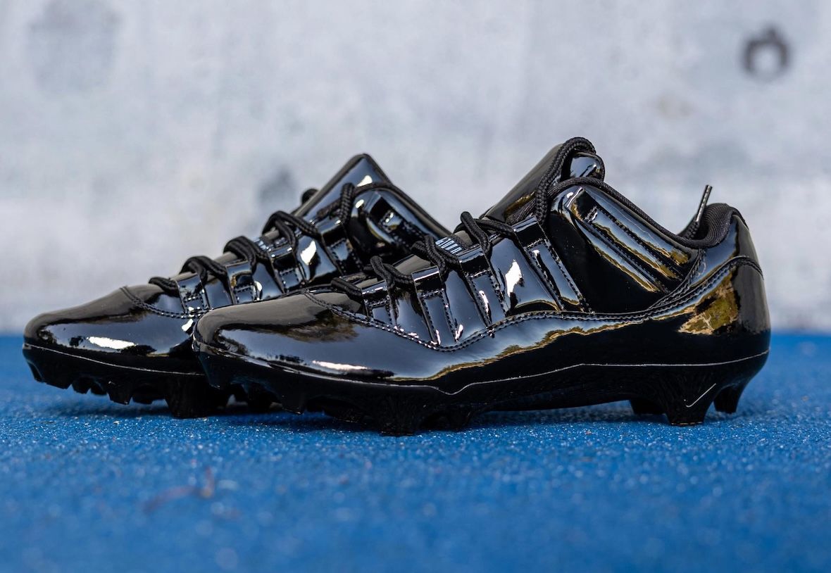 Par de botines Air Jordan 11 Gammas de UCLA en charol negro, apoyados sobre una superficie azul
