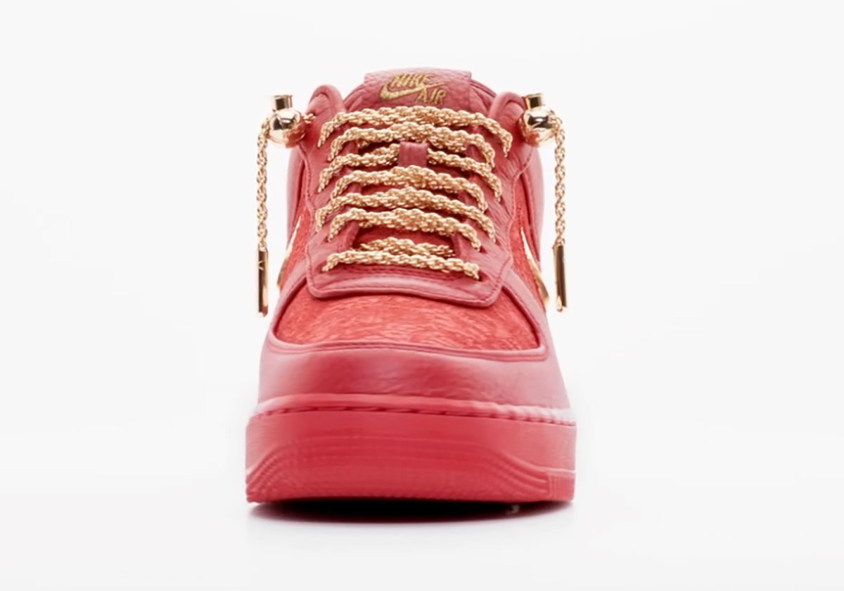 Victor Solomon x Nike Air Force 1 Low Trophies rojo de frente sobre fondo blanco, con los cordones de soga dorados, la lengüeta con el logo dorado y la puntera roja